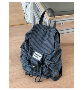 Dettaglio dello zaino in nylon a quadri blu-grigio con coulisse ed etichetta del marchio tessuta