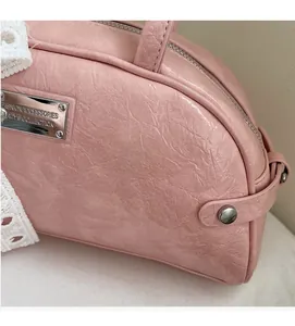 Détail du sac à main rose montrant la texture plissée, le logo et la dentelle blanche