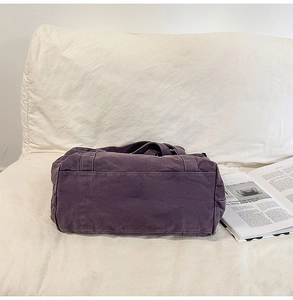 Detail of a purple canvas tote bag with side pocket on a sofa with magazines