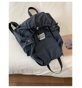 Dettaglio dello zaino in nylon a quadri blu con chiusura a coulisse ed etichetta tessuta