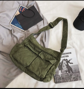 Detail of dark green canvas messenger bag featuring dual large utility cargo pockets