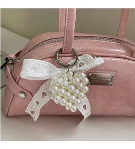 Gros plan du sac froncé rose avec nœud en dentelle et breloque cœur en perles