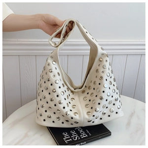 Gros plan du sac hobo blanc crème avec rivets punk argentés et détails d'œillets métalliques