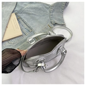 Detail view of the silver snake-pattern handbag showing interior lining and metal handle