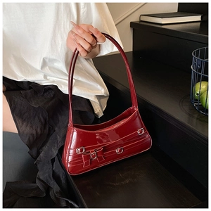 Detail of dark red patent leather shoulder bag with silver buckles and bow decoration