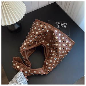 Détail d'un sac seau en cuir marron de style punk avec des rivets métalliques argentés