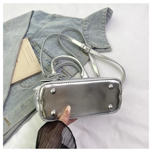 Detail view of silver shell bag showing protective metal feet and adjustable strap