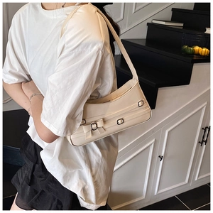 Detail of cream white underarm bag with bow decoration and metal buckle strap design