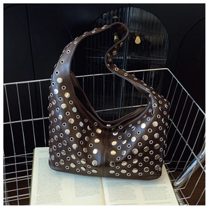 Détail du sac seau marron foncé avec clous et œillets argentés dans un panier