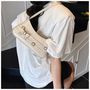 Detail of cream bow-knot underarm bag with glossy leather and silver metal buckles