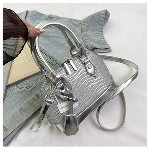 Detail of silver shell bag with glitter wave texture and metallic handles shown on denim