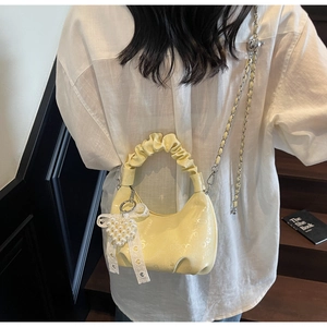 Vue détaillée du sac à main plissé jaune avec breloque cœur en perles et nœud dentelle.