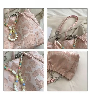 Close-up of pink tote bag with heart-shaped jacquard and colorful beaded chain detail