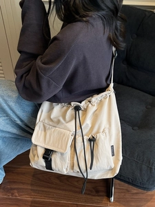 Minimalist beige nylon crossbody bag with drawstring closure and functional utility pockets