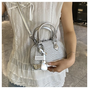 Detail of mini silver shell bag featuring textured wavy glitter and metal strap