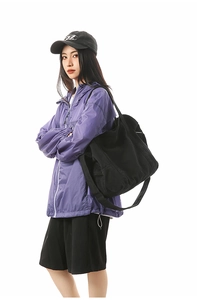 Detail showing a large black canvas tote bag paired with a purple outdoor windbreaker