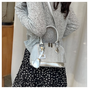 Detail of silver shell bag featuring metallic snakeskin texture and slim shoulder strap