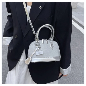 Detail of silver mini shell bag featuring dual handles and metallic leather textures