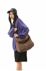 Close-up of a large dark brown canvas tote bag with functional pockets for streetwear