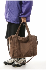 Detail of a large brown canvas tote bag with side pockets and adjustable shoulder strap