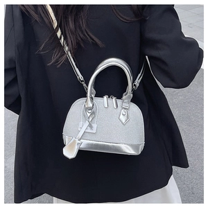 Close-up of silver glitter shell bag with metallic handles on a black blazer outfit