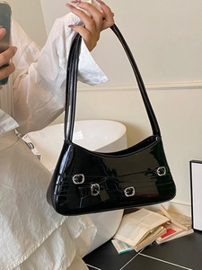 Chic black patent leather underarm bag with silver buckle and bow detail, handheld view