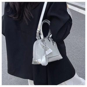 Detailed street shot of a silver shell bag with metallic finish and slender strap