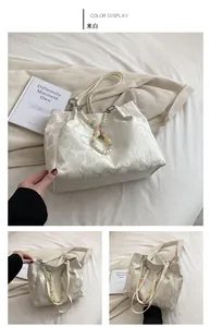 Detail of off-white tote bag with 3D heart embossing and colorful beaded charm