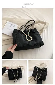 Detail view of black embossed tote bag with leaf texture and colorful bead chain