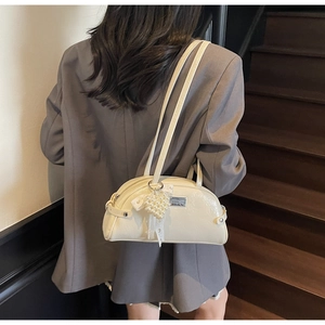 Détail du sac bowling crème avec nœud en dentelle blanche et pendentif cœur perlé