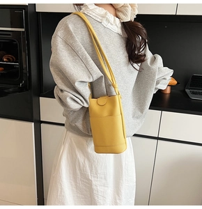 Gros plan d'un sac bandoulière jaune grainé pour téléphone porté dans une cuisine moderne