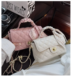 Detail of quilted chain bags with silk scarf handles on car seat for a luxury lifestyle view