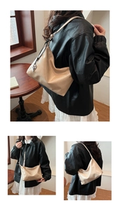 Detail of beige underarm bag with silver heart charm shown on a casual model's outfit
