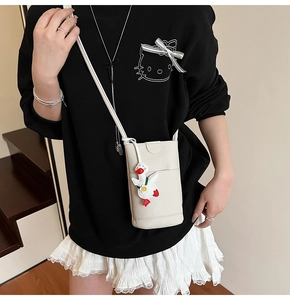 Détail du sac à téléphone en cuir litchi blanc avec pendentif canard et bandoulière