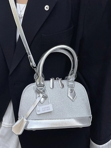 Silver metallic shell handbag with adjustable strap shown on a model's outfit