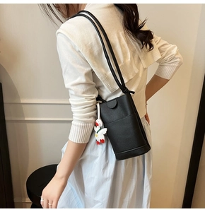 Detail of mini black pebbled leather crossbody bag with a cute white duck pendant