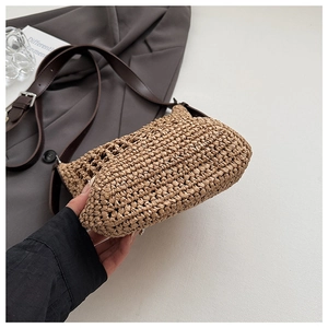 Dettaglio borsa shopper in paglia intrecciata con cinturini in pelle marrone e fibbia argento