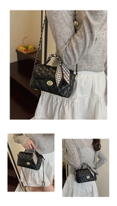 Close-up of black quilted chain bag with elegant silk scarf wrap on the handle
