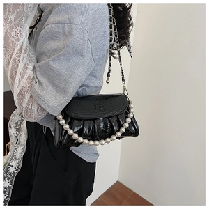 Dettaglio di borsa nera a pieghe alla moda con catena di perle su una modella
