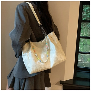 White tote bag with heart patterns and colorful bead handle shown on model's shoulder
