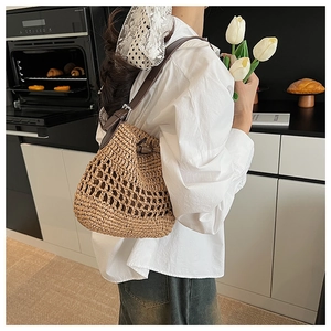 Vista dettagliata della borsa tote in paglia intrecciata con spalline in pelle marrone