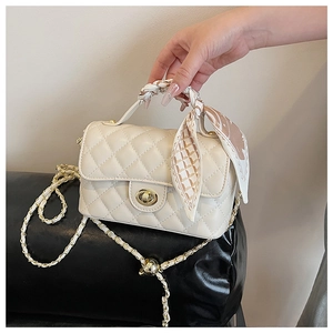 Close-up of quilted beige crossbody bag with silk scarf handle and golden twist lock