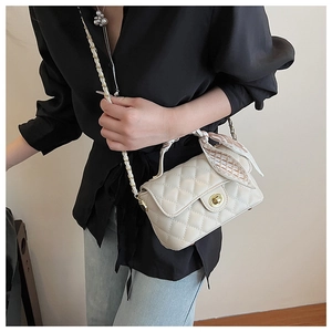 Detailed side view of beige quilted chain bag with elegant silk scarf and gold lock