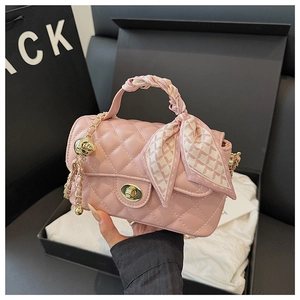 Detailed close-up of pink quilted crossbody bag with golden clasp and scarf handle