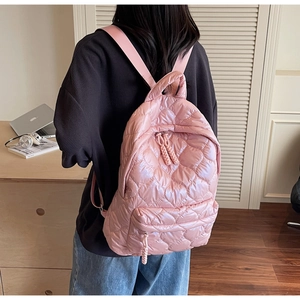 Close-up of pink quilted backpack with heart patterns and padded shoulder straps