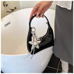Detail of glossy black patent leather bucket bag with silver star charm and sleek crescent shape