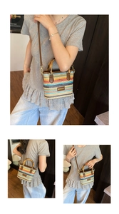 Detail of woven straw bucket bag with colorful stripes, bamboo handle and leather strap