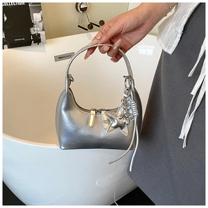 Silver metallic crescent handbag with star charm and tassel in a minimalist setting