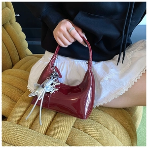 Detail of burgundy patent leather hobo bag with shiny silver star charm and accessories