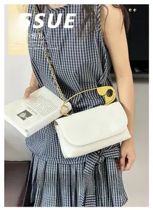 Sac blanc à chaîne avec grande poignée épingle de sûreté dorée sur une robe à carreaux